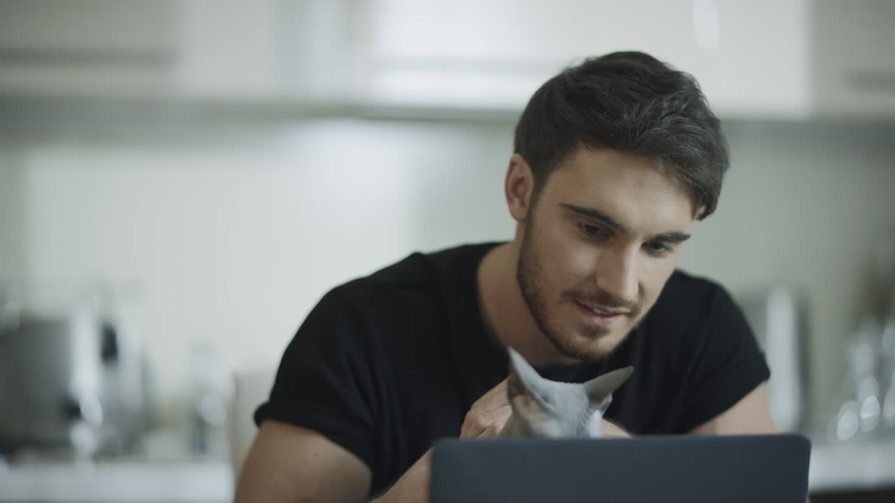 hombre hipster tocando al gato en el lugar de trabajo en casa. hombre feliz trabajando en una computadora portátil