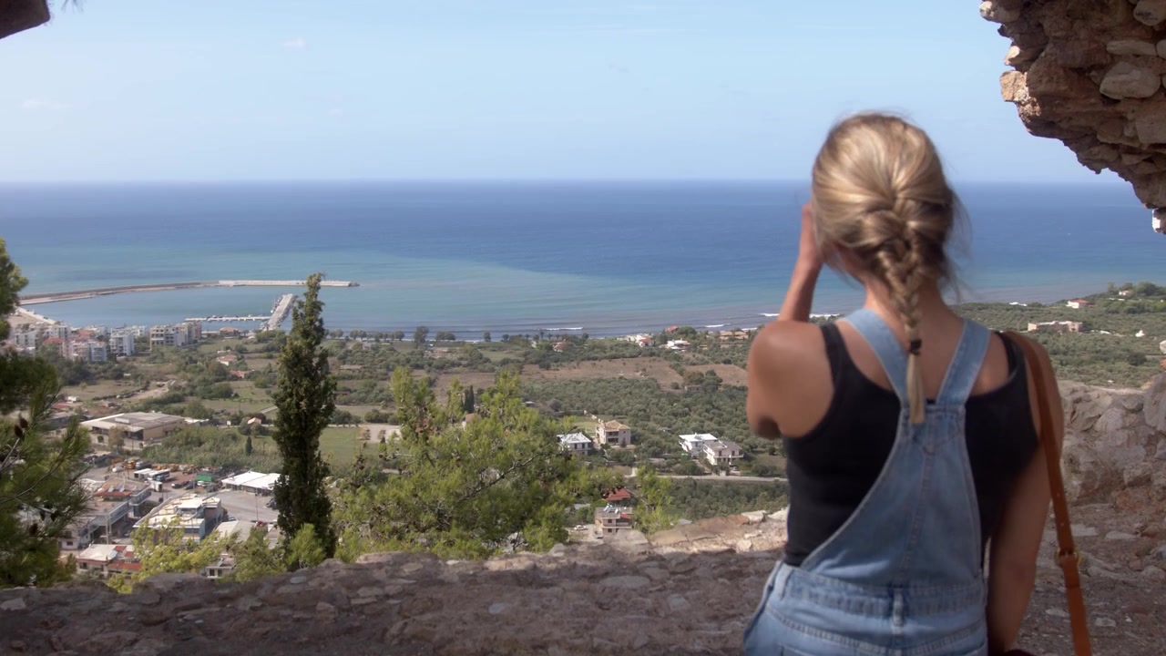 Woman discovering a beach view through a hole in a wall