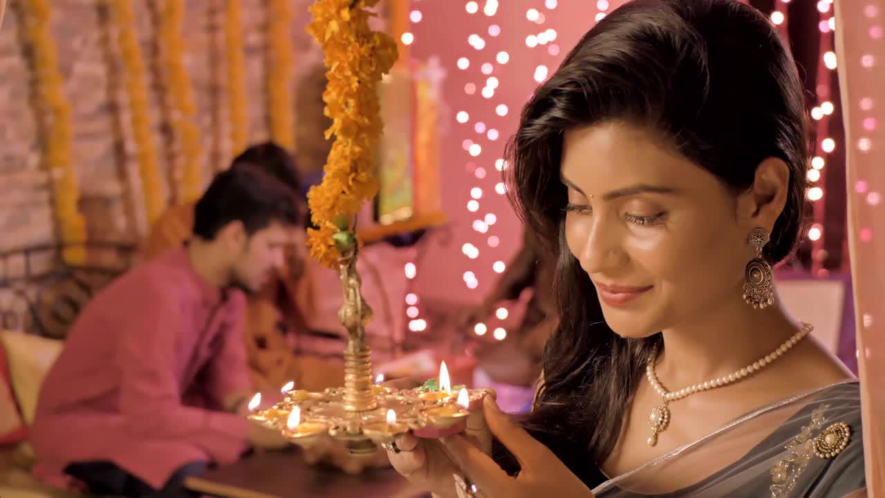 Beautiful woman holding a earthen oil lamp in hands and smiles.