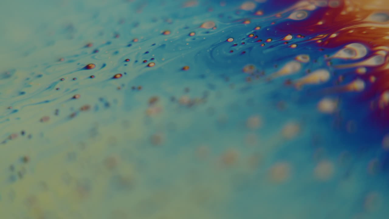 toma macro de pequeñas partículas que fluyen hacia un líquido de color arcoiris
