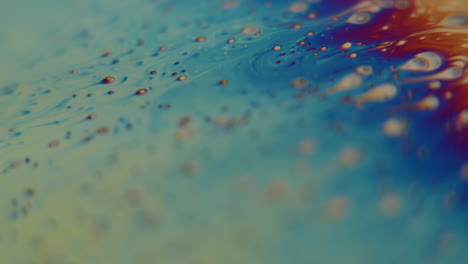 macro shot of small particles flowing into a rainbow colored liquid