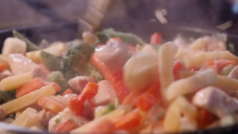 de cerca: pollo y verduras al vapor, cocinados en una sartén caliente