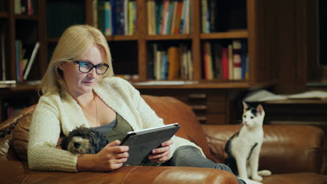 a woman reads a book in a tablet sits in the luxurious back of the library