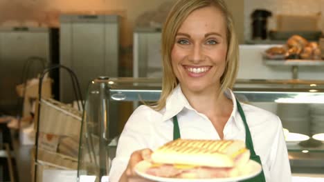 deli worker offering a panini