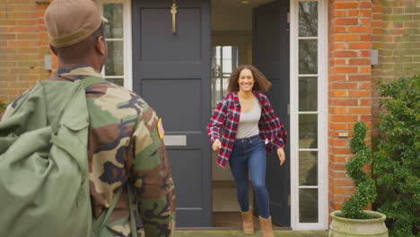 american soldier in uniform returns home to family on leave hugging wife and children outside house