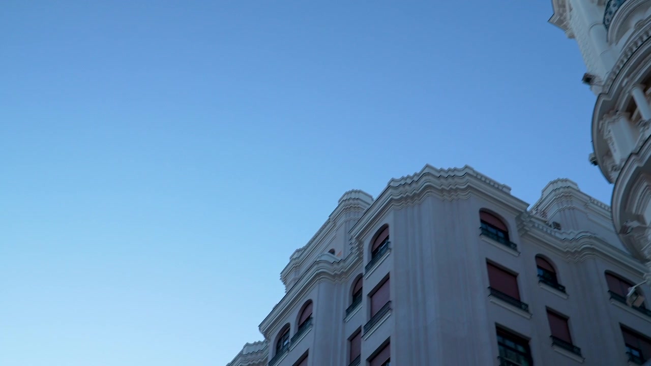 Inquadratura dal basso di edifici storici ornati a Madrid con un semaforo rosso che attraversa l'inquadratura. Adatto per contenuti di viaggio e stile di vita urbano