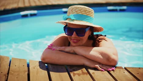 woman relaxing by the poolside in a straw hat and sunglasses enjoying a sunny day