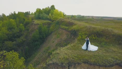 couple kisses on steep riverbank near field upper view