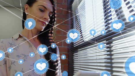 red de iconos digitales contra una mujer de negocios caucásica que usa tableta digital en la oficina