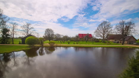 Cabañas-Junto-Al-Lago-Bajo-Un-Cielo-Azul-Con-Nubes-Blancas-Flotando