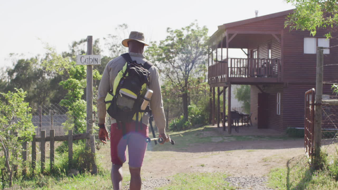 Senior african american man hiking with trekking poles on sunny day, slow motion