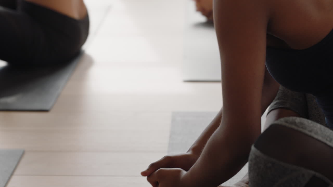 mujer de yoga saludable practicando oración posan joven afroamericana disfrutando de la meditación espiritual en el estudio con un grupo de mujeres multirraciales