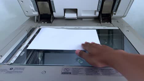 human hand takes paper from inside a photocopier