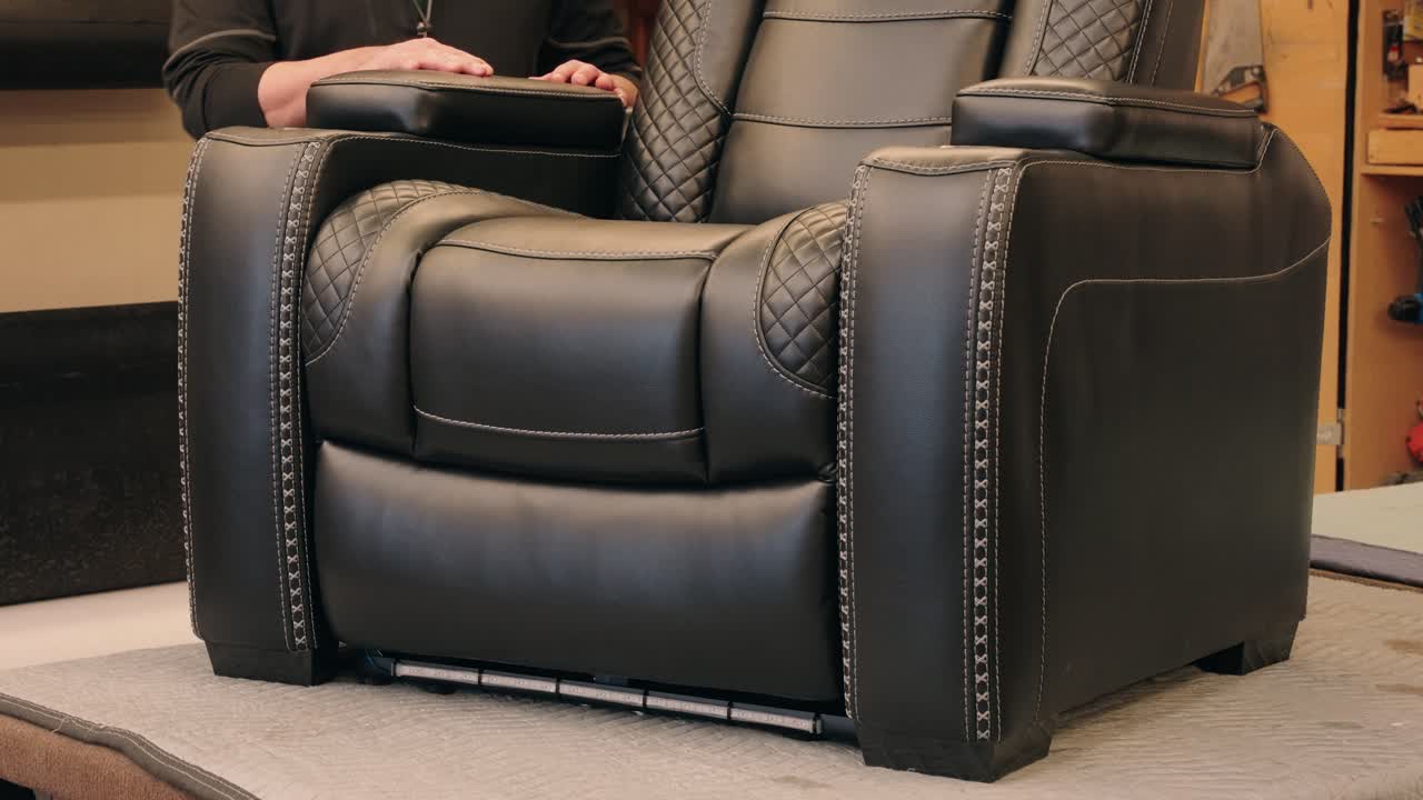 Worker steps behind black leather chair on bench and poses for camera demo