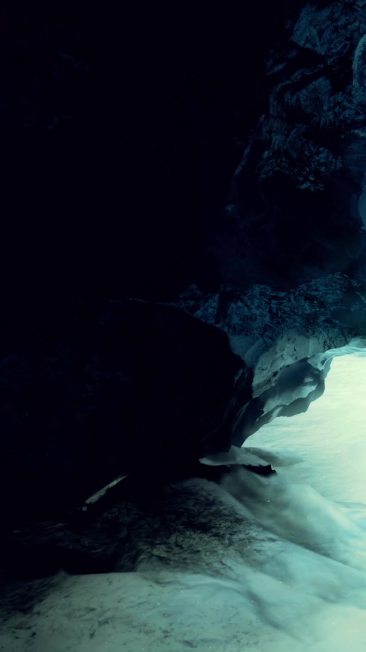 Exploration of a dark cave with faint light illuminating the rocks