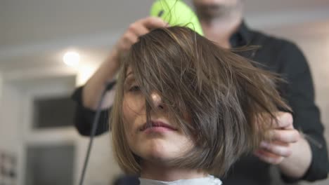 junge frau, die sich im schönheitssalon die haare anziehen lässt