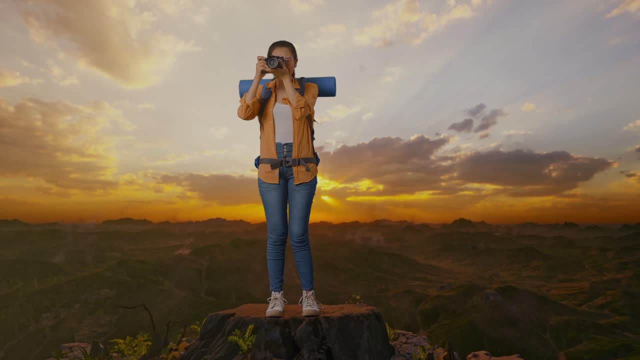 mujer tomando una foto en la cima de la montaña al atardecer
