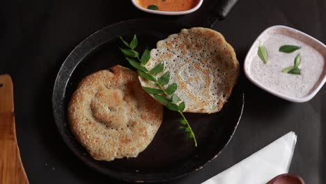 rotating south indian food set dosa with curry and chutney on black background