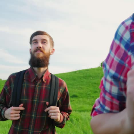 a couple of tourists with backpacks are walking along the crest of a large green hill 5