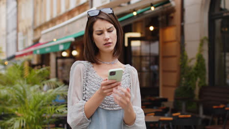 surprised young woman use smartphone loses, bad news, fortune loss, fail outdoors in city street