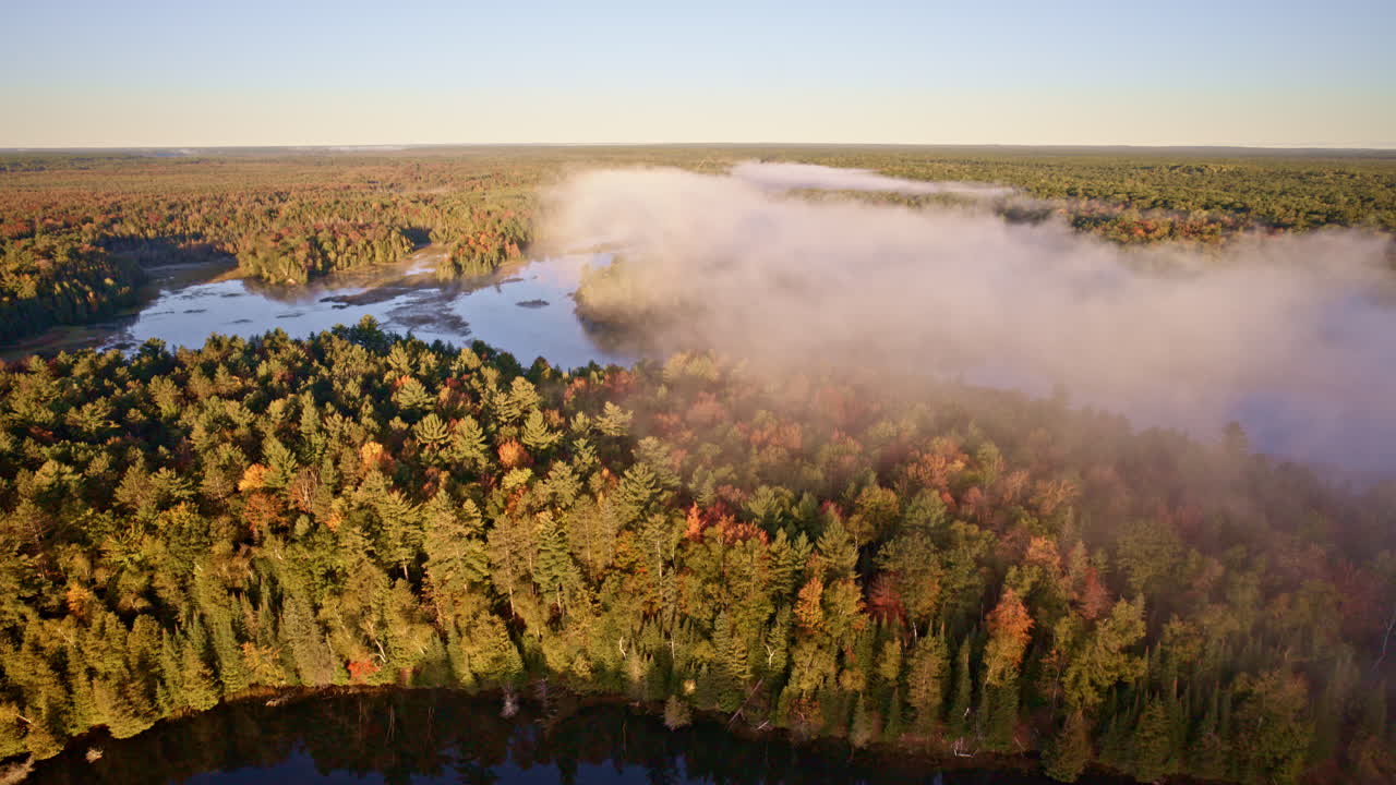 Drone flies above water as sunrise mist begins to rise