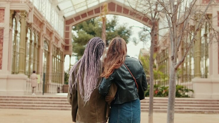 Two Young Women Walking Arm in Arm in a Park