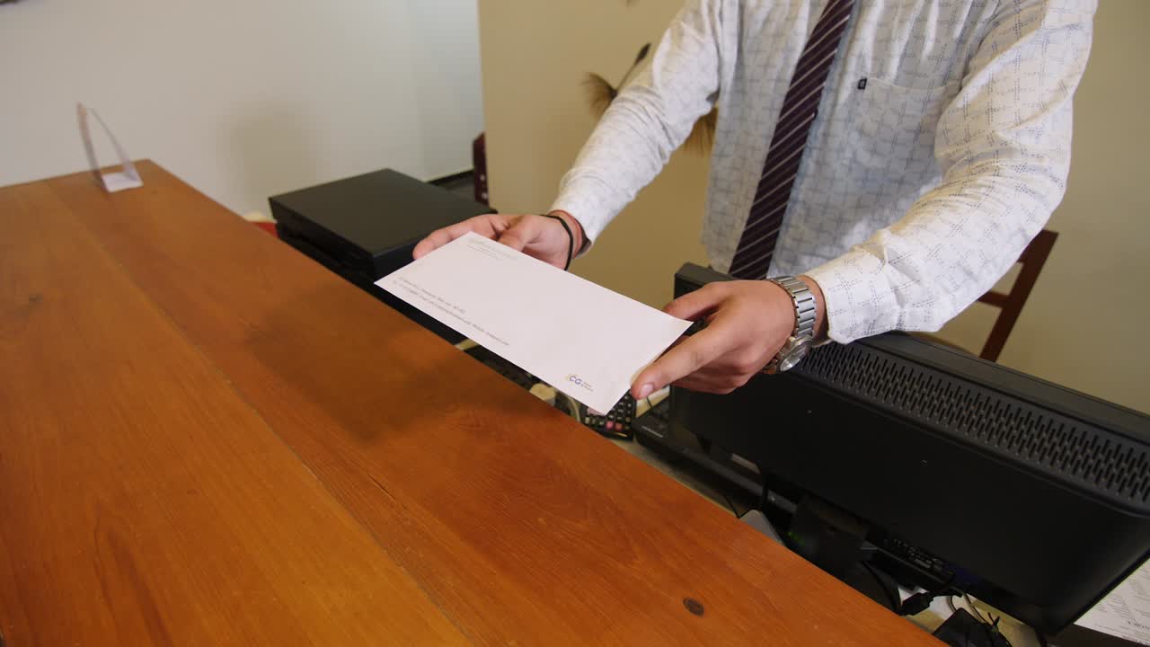 The receptionist handing over the envelope.