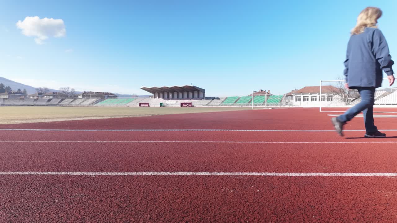 Middle aged Woman healthy outdoor exercise around sports stadium track