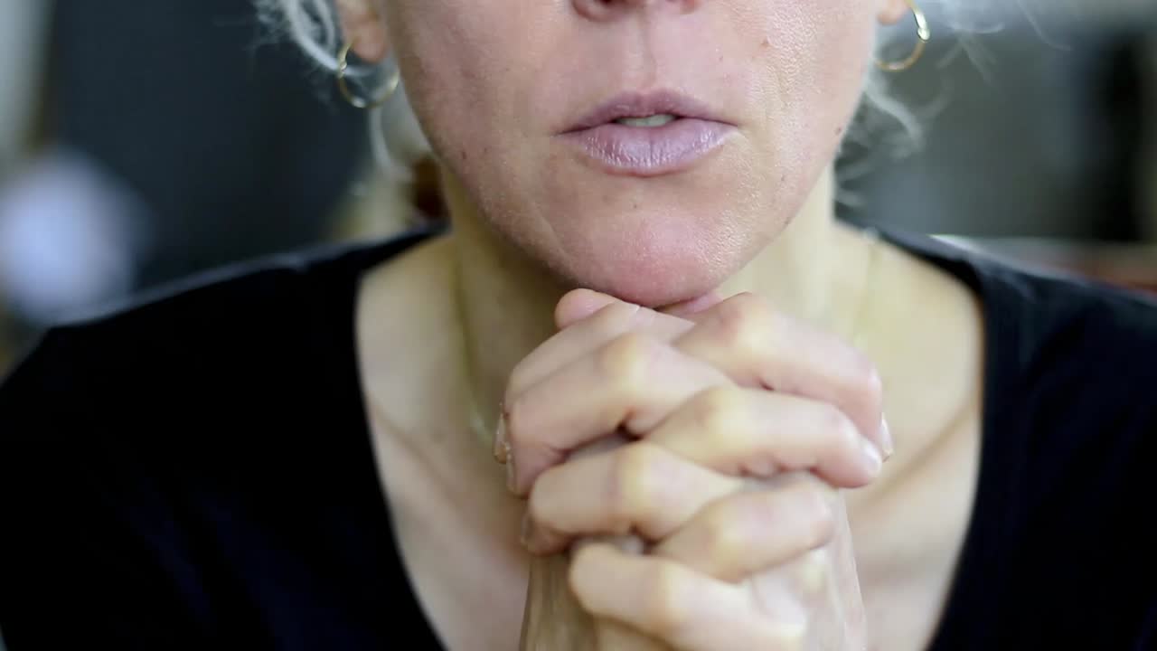 donna che prega con la mano sul viso su sfondo grigio con persone stock video