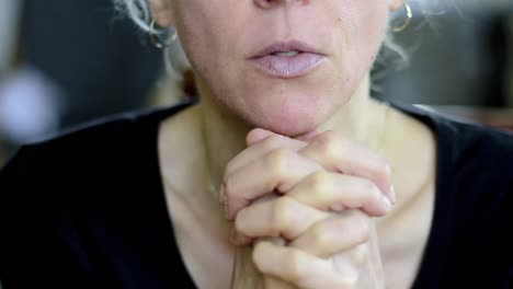 woman-praying-with-hand-over-her-face-on-grey-background-with-people-stock-video