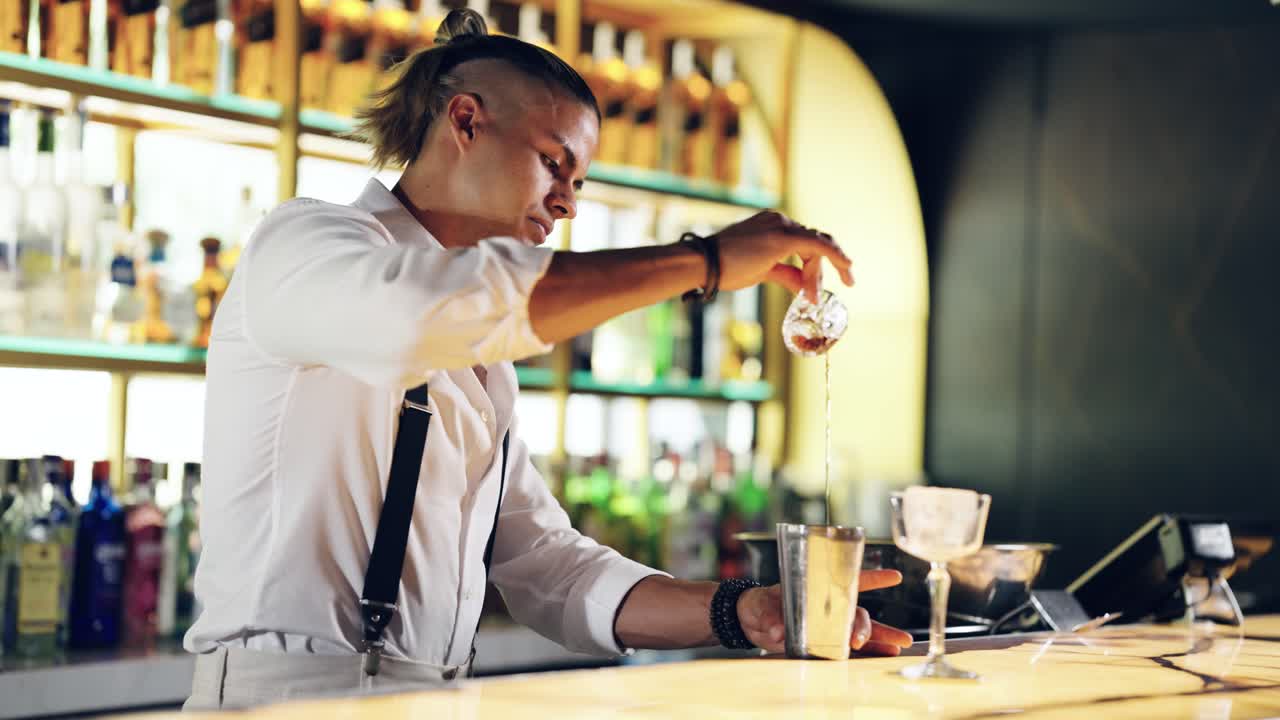 Barman che versa un cocktail in uno shaker in un bar moderno