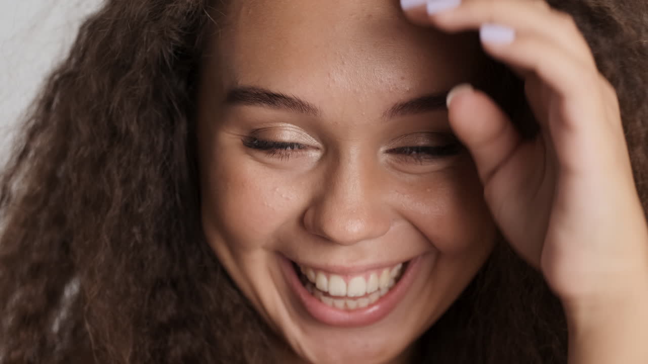 una mujer caucásica de cabello rizado sonriendo a camara.