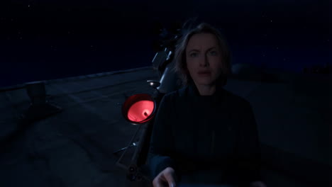 woman stargazing with a telescope on a rooftop at night