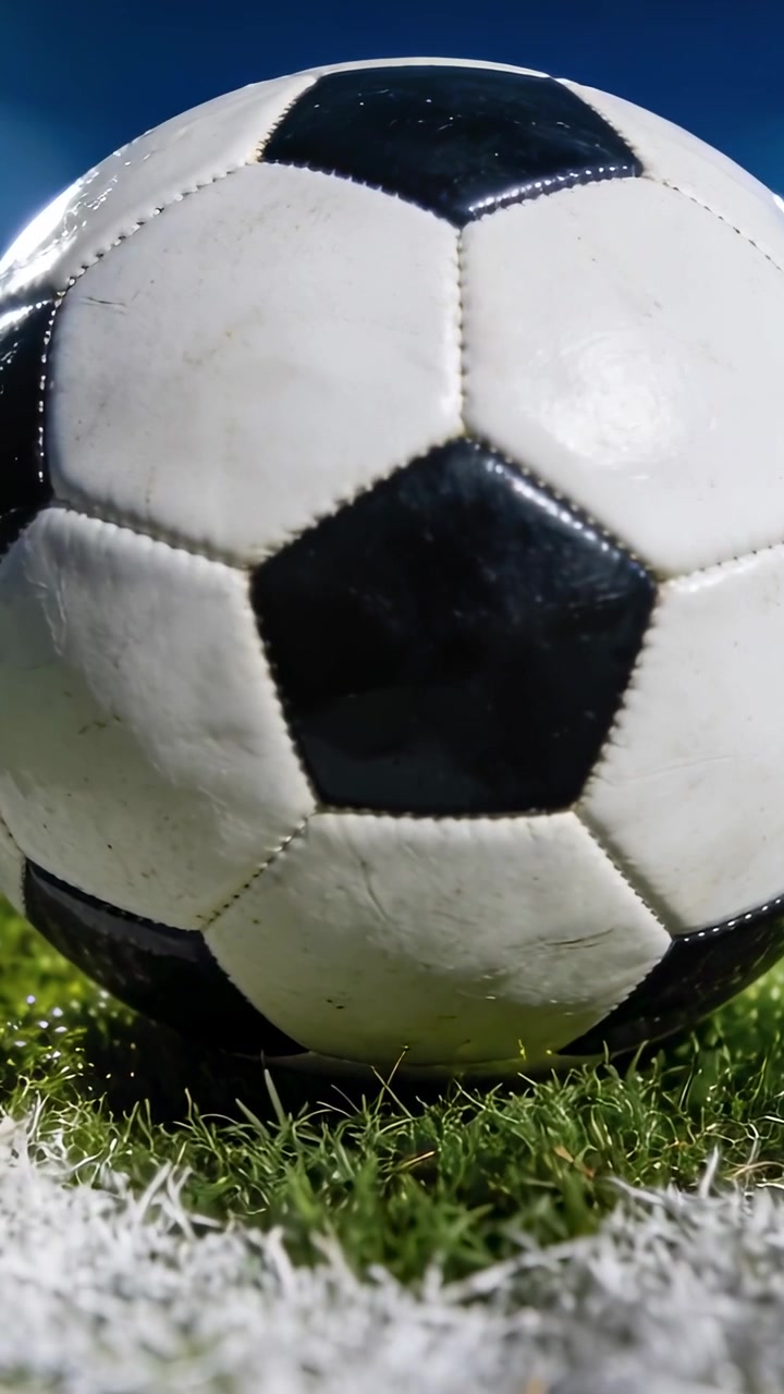 Video vertical: Cámara haciendo zoom en un balón de fútbol apoyado en la línea blanca del campo, mostrando su textura cosida.