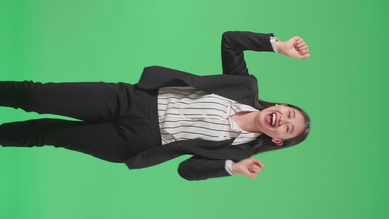 A Smiling Asian Business Woman Dancing While Standing On Green Screen Background In The Studio