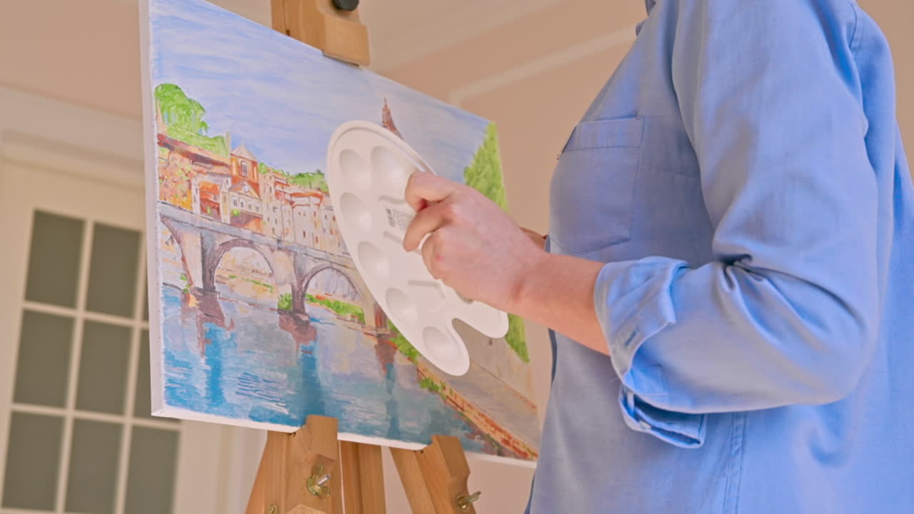 Caucasian woman painting a picture with a palette in her hands, indoors. Slow motion