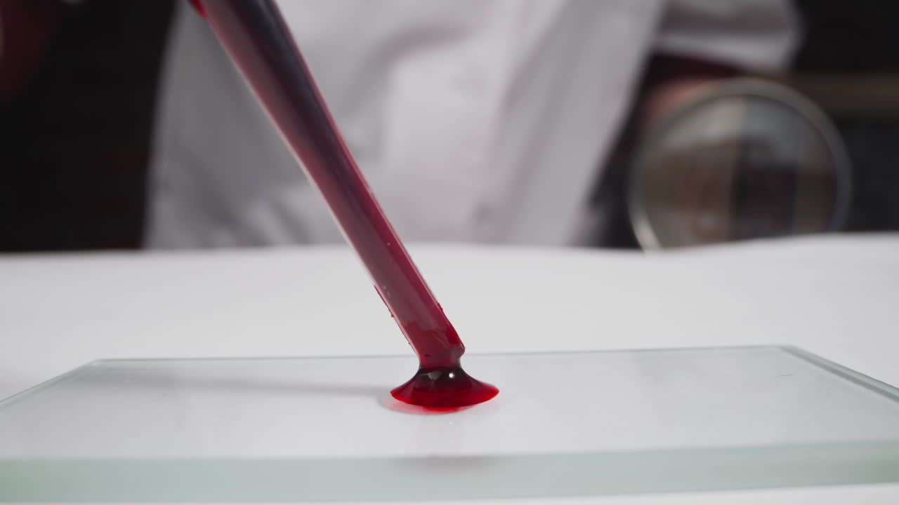 un especialista en túnica gotea sangre en un portaobjetos en el laboratorio