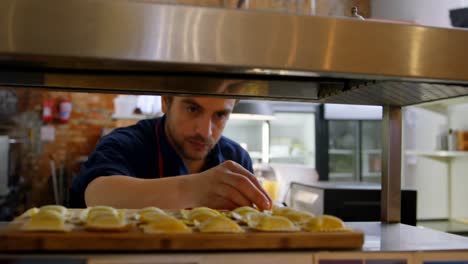 Male-baker-arranging-baked-food-in-kitchen-4k