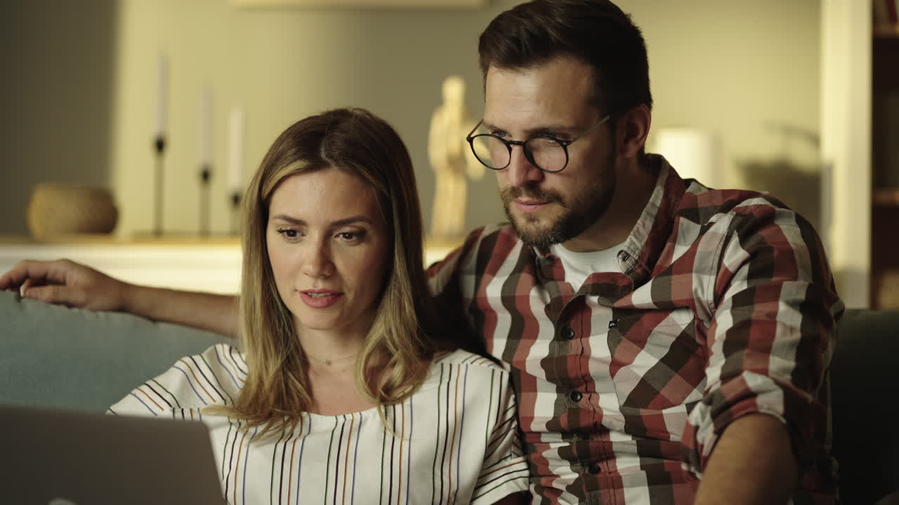 A couple watching a laptop together indoors