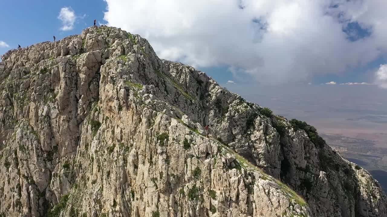 un hombre negro local camina con cuidado por el borde de la montaña con un acantilado empinado justo al lado de él