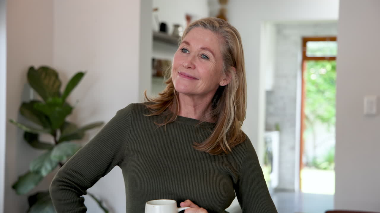 Smiling senior woman holding coffee cup at home, enjoying cozy holiday moment