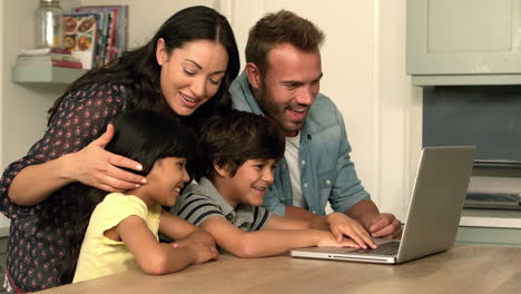 happy family using laptop together in the kitchen