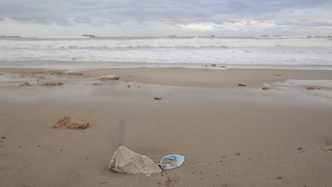 medical mask washed by sea water on beach