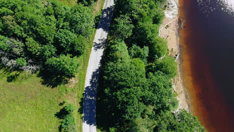 Luftaufnahme-Des-Red-Water-Lake-Neben-Grünen-Bäumen-Und-Einer-Schmalen-Straße