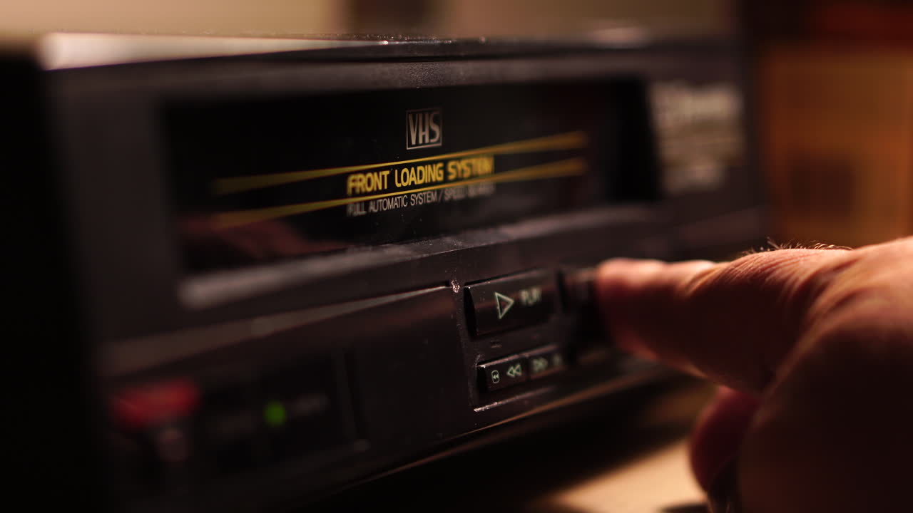 Close-up of a hand operating a vintage VHS video cassette recorder