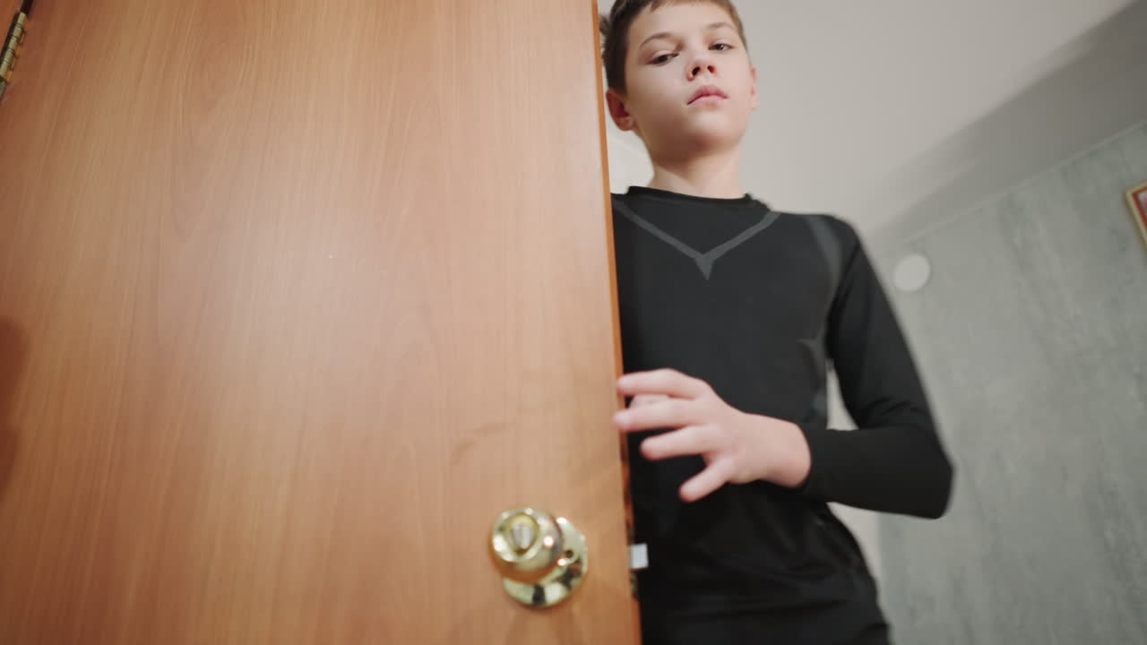 Ungdom går försiktigt in. Tonåring närmar sig försiktigt dörröppningen. Ung man öppnar försiktigt trädörren i hallen. Pojke i tonåren drar försiktigt upp trädörren i en smal korridor.