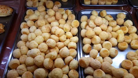 several cheese puffs being displayed at a brazilian bakery showcase.