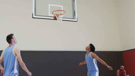 diverse male basketball team training at indoor court and missing basket, slow motion