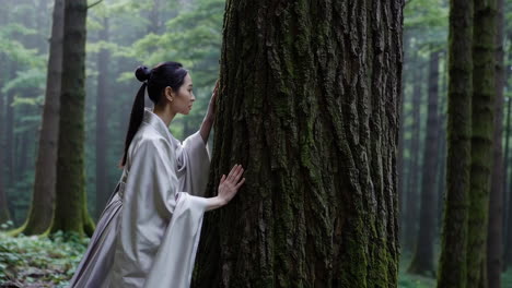 woman in traditional dress touching ancient tree in misty forest