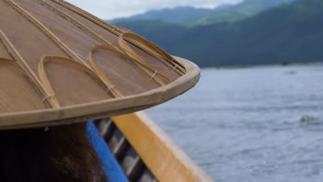 traditional myanmar bamboo hat on person boating across inle lake